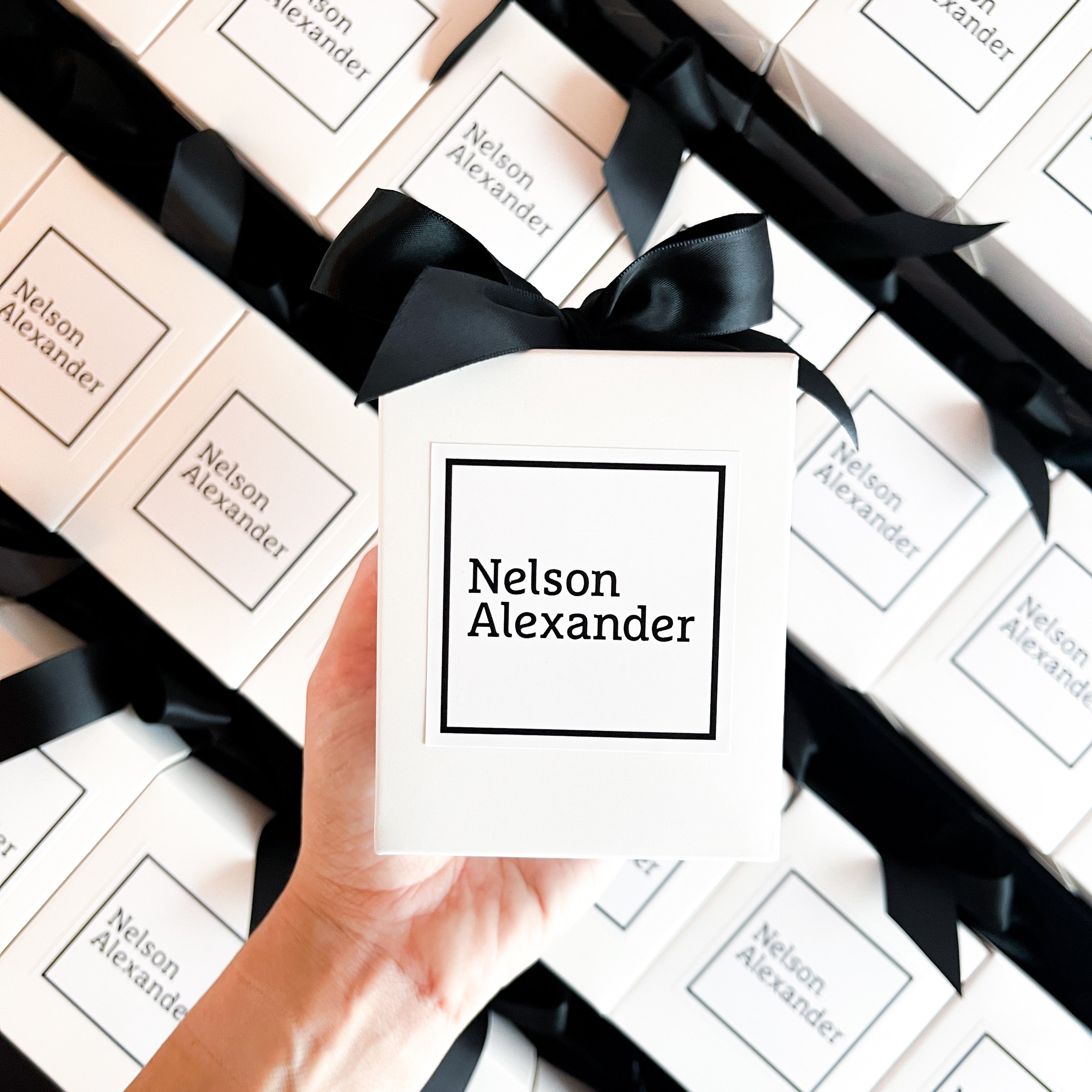 200g Medium custom branded candles for Nelson Alexander with minimalist black and white logo and black ribbon, ideal for real estate client gifting.