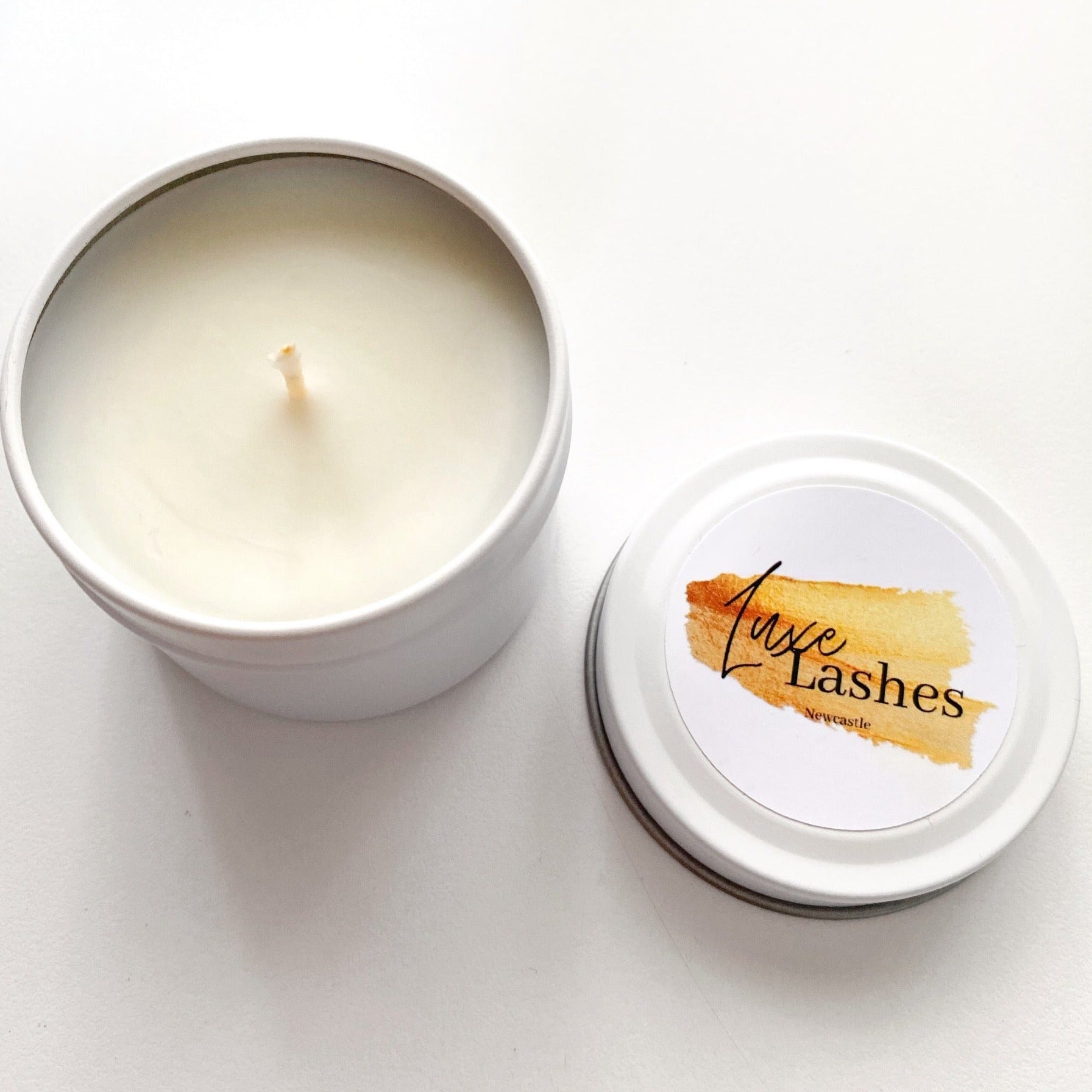 Custom-branded candle tin for Luxe Lashes Newcastle with white base and orange brushstroke logo, made by Lovr Designs.