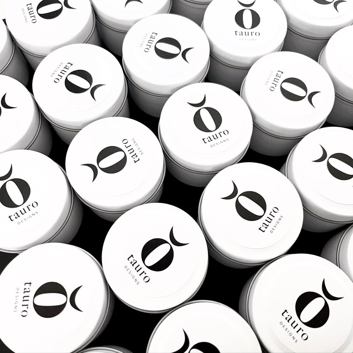 Custom-branded 60g candle tins for Tauro Designs featuring minimalist black and white circular logo, handcrafted by Lovr Designs.