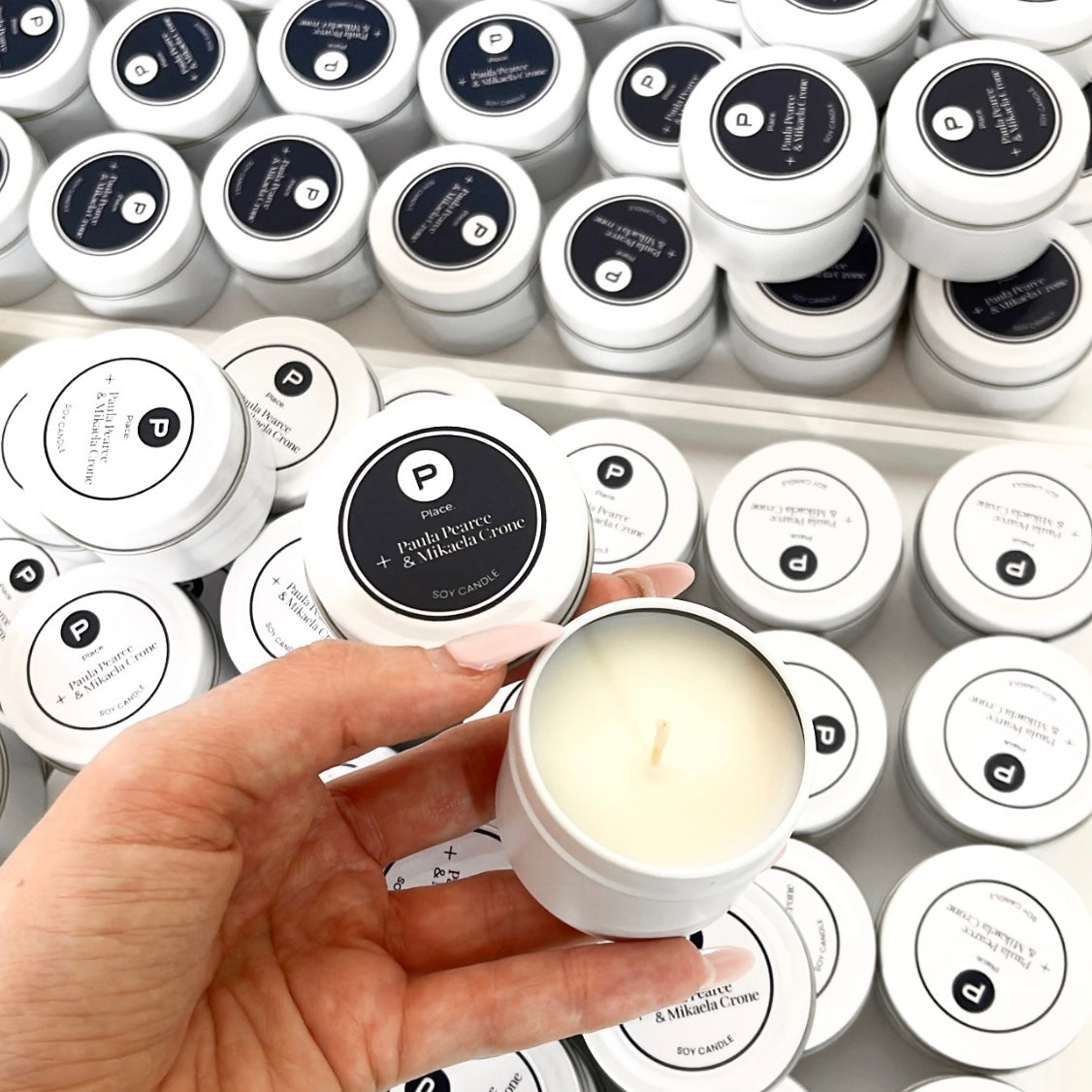 Custom white tin candles with black and white branded labels for Place Estate Agents, styled in bulk for gifting.