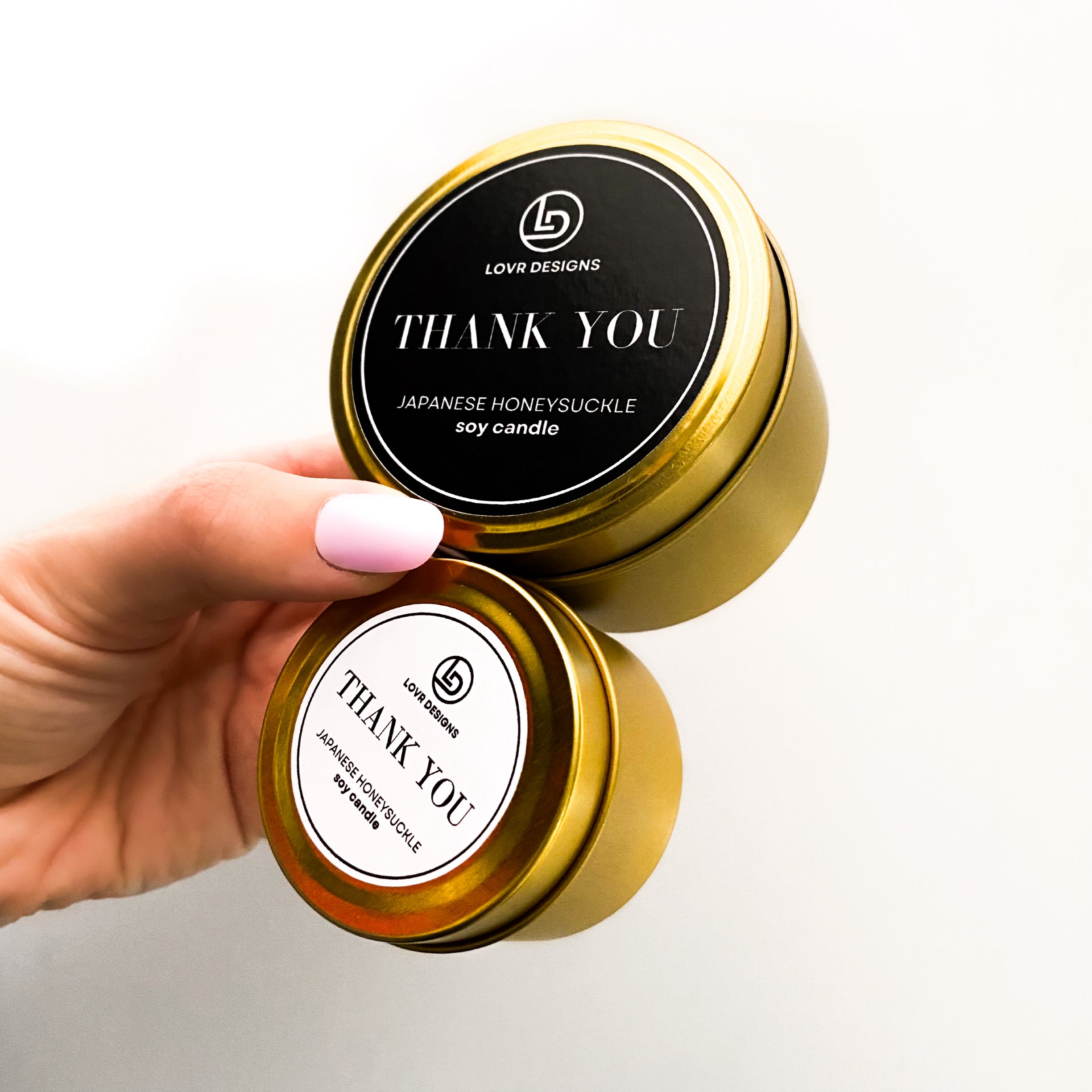Custom-branded thank you candles in gold tins by Lovr Designs, featuring Japanese Honeysuckle scent with both black and white label designs.