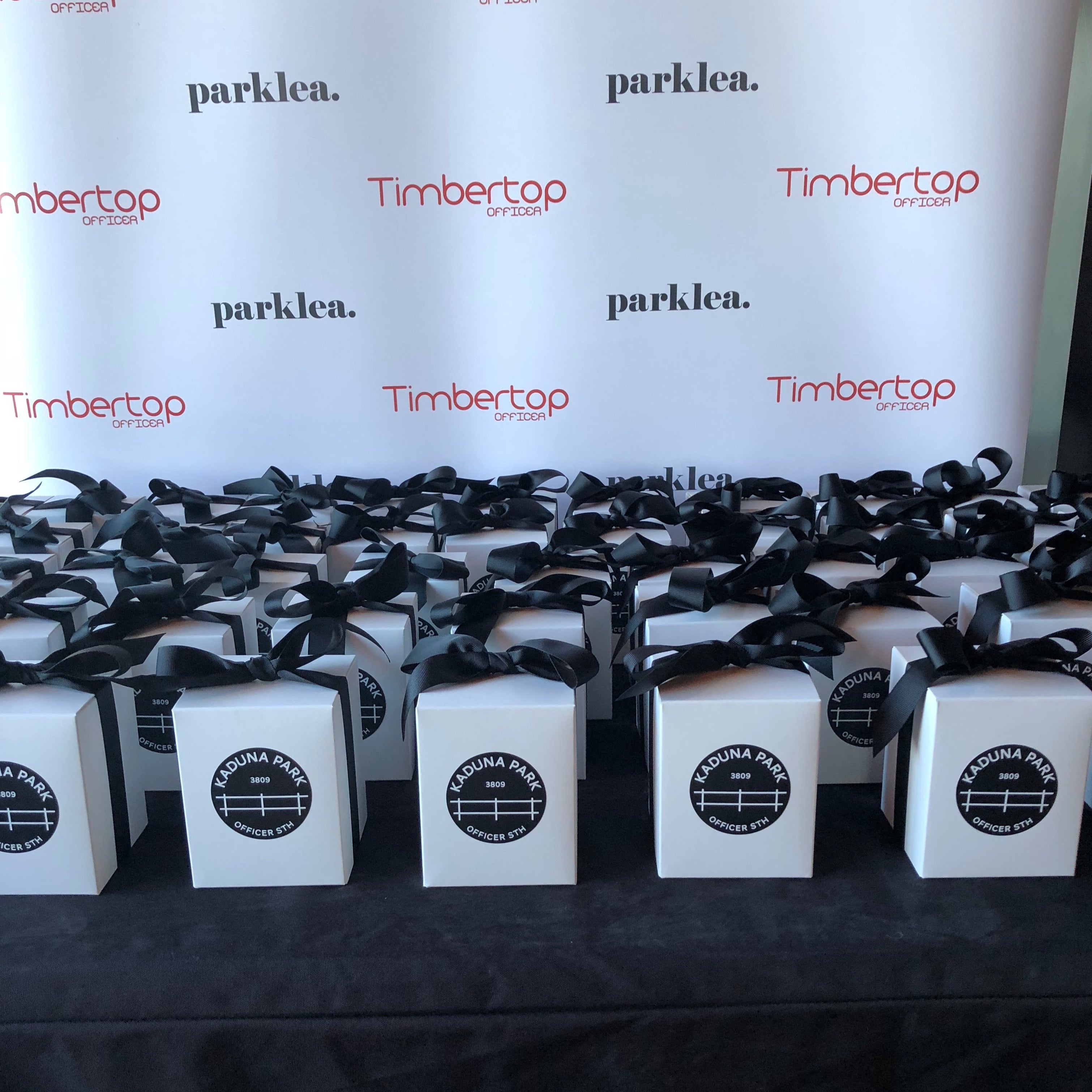Custom Event Candles for Kaduna Park, Parklea with black ribbon and circular black and white logo, styled in rows for a corporate event.