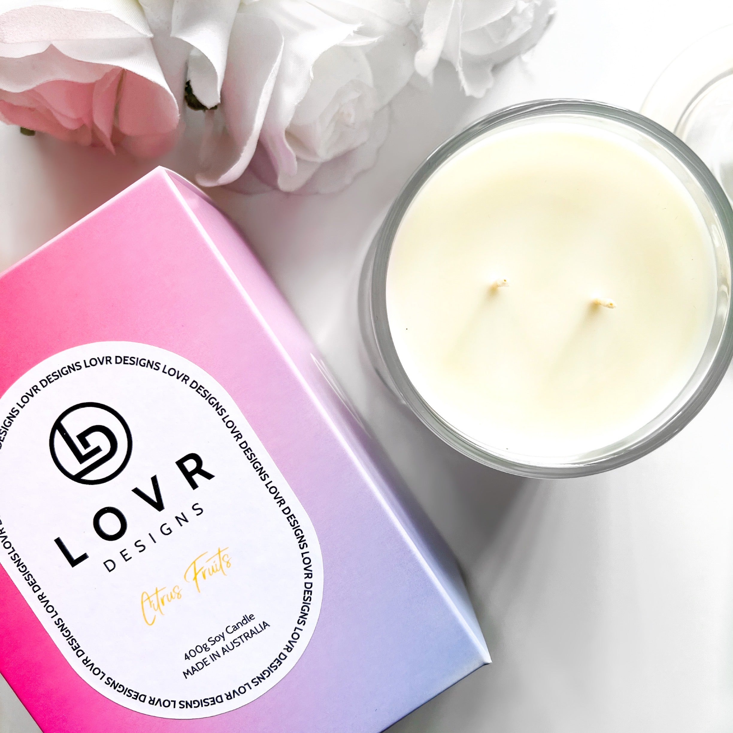 Top view of Citrus Fruits soy candle and Lovr Designs signature box, surrounded by white flowers — XL 400g size.