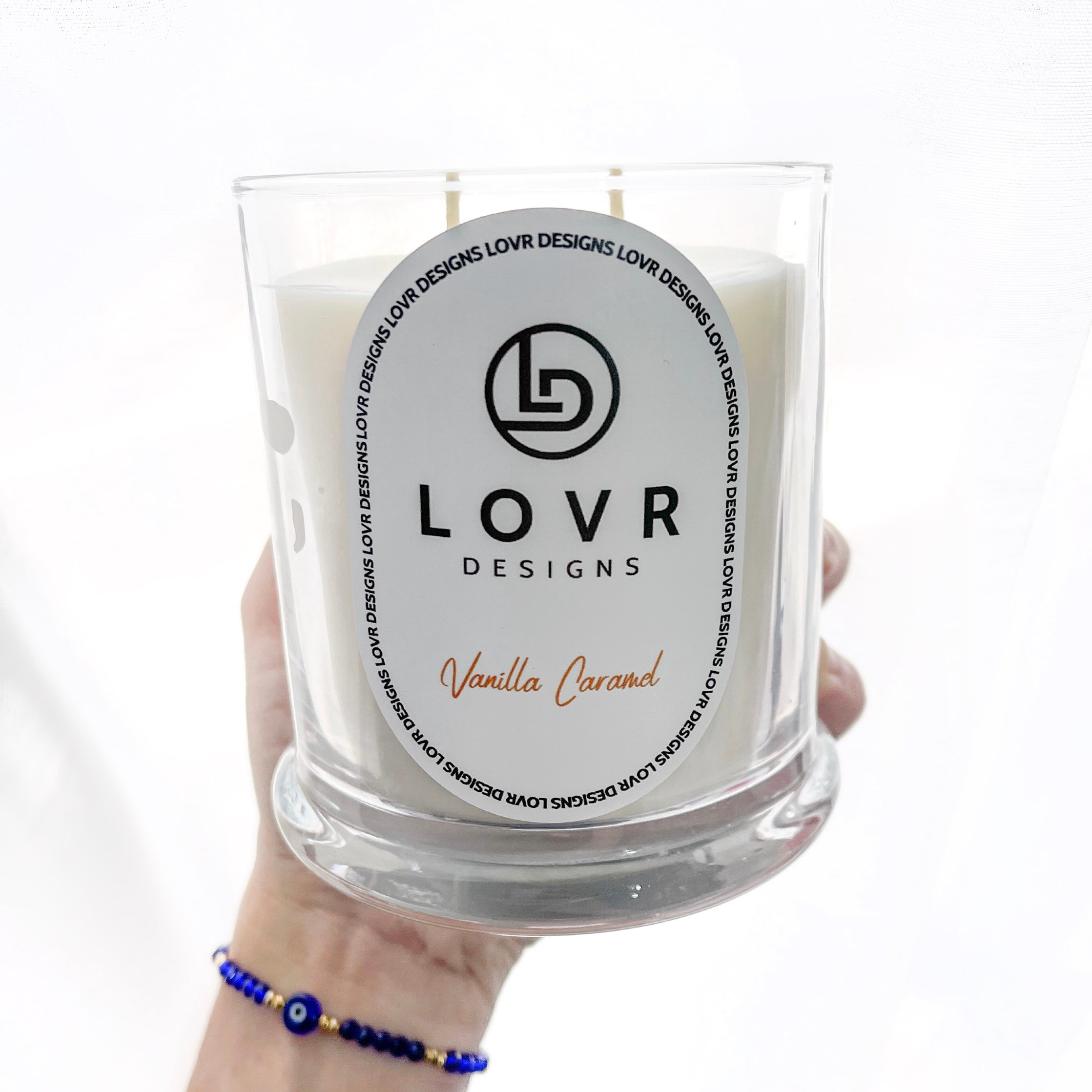 Hand holding Lovr Designs Vanilla Caramel 400g scented soy candle – elegant and minimalist clear glass jar.