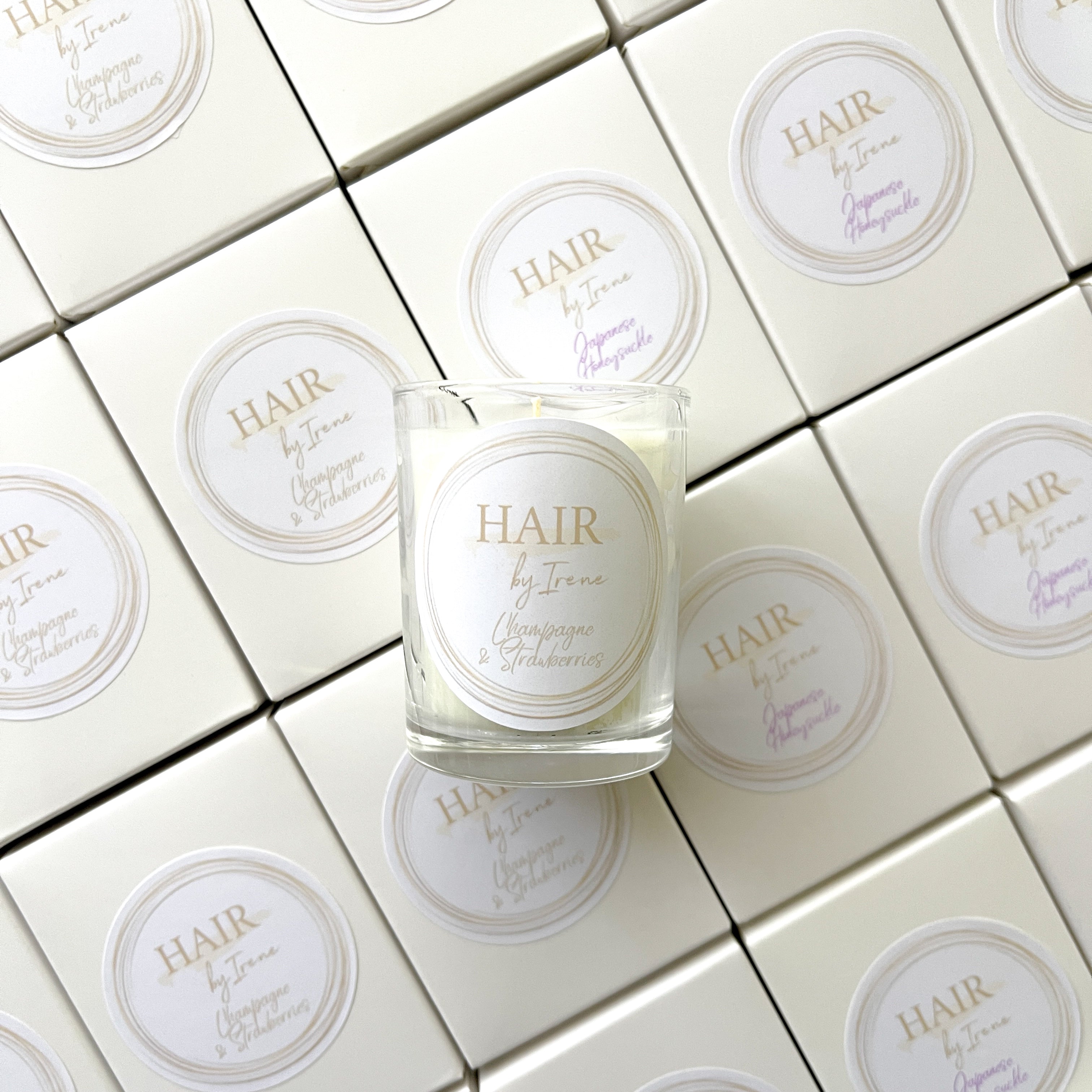 Custom branded 60g soy candles for Hair by Irene featuring Champagne & Strawberries and Japanese Honeysuckle scents. Luxury salon client gifts in soft neutrals.
