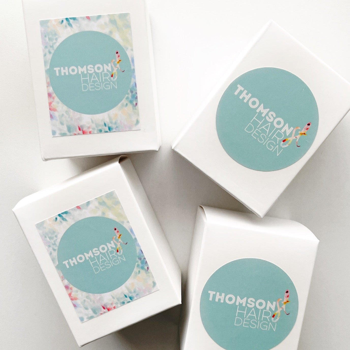 Custom branded 60g soy candles for Thomson Hair Design. Colourful pastel packaging with logo labels, ideal for salon client gifts or promotional favours.