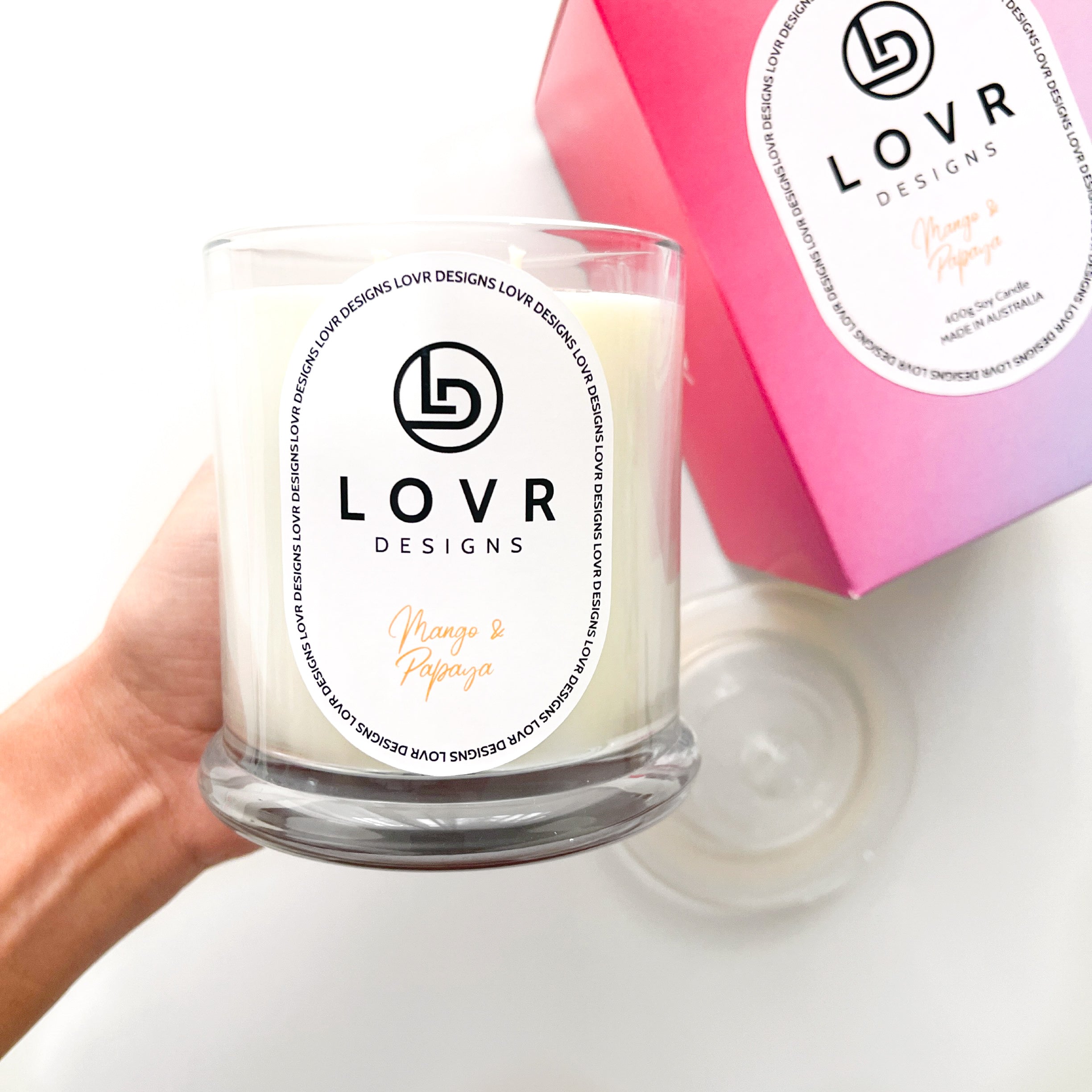 Hand holding Lovr Designs Mango & Papaya candle with matching pink gift box