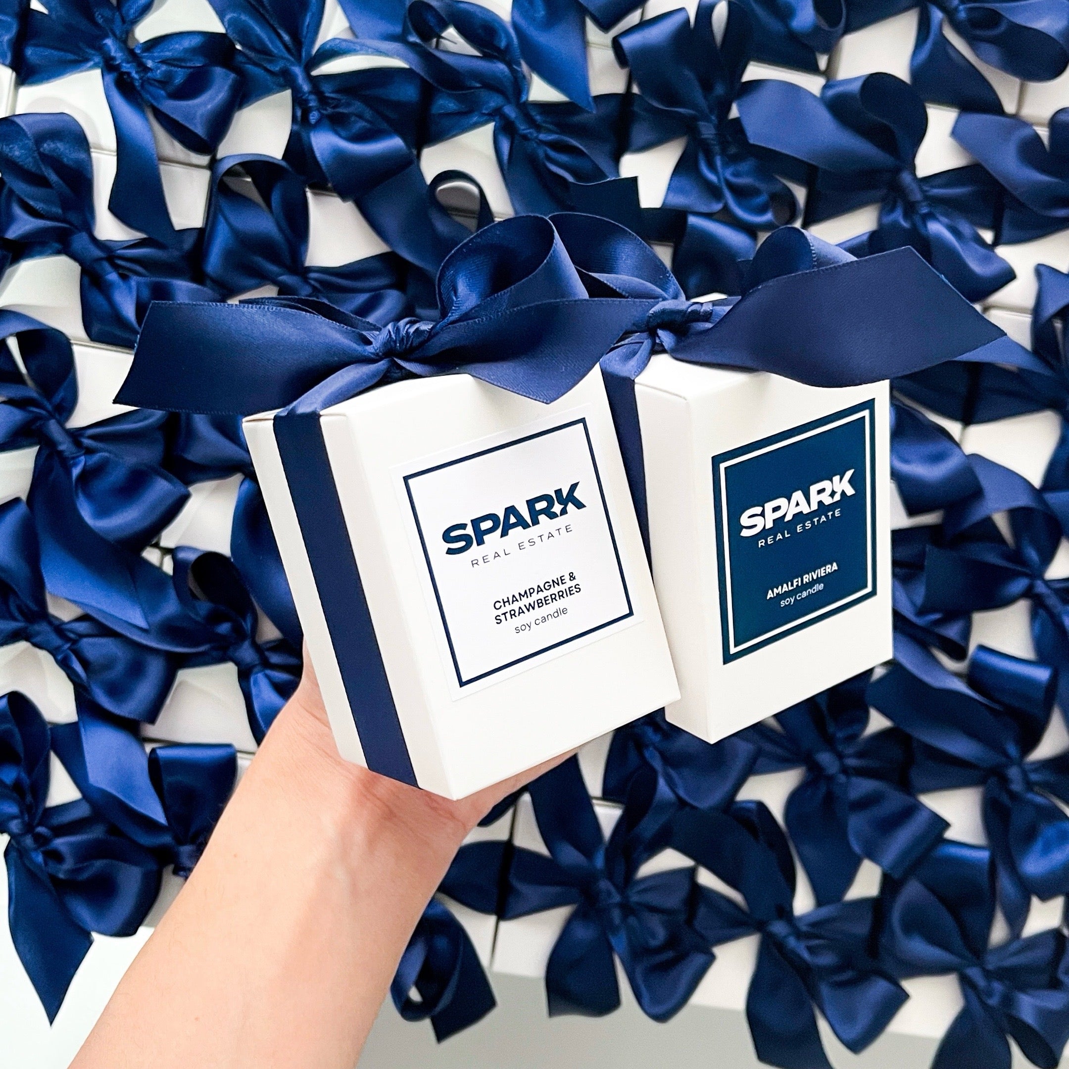 Branded gift candles for Spark Real Estate with navy ribbon and custom labels