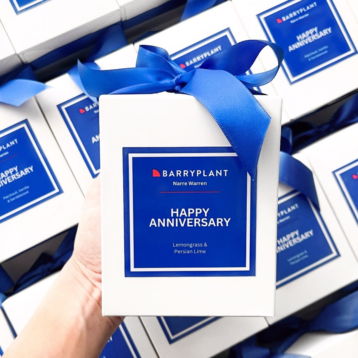 Custom branded 300g candle for Barry Plant Narre Warren with 'Happy Anniversary' label in blue, scented in Lemongrass & Persian Lime.