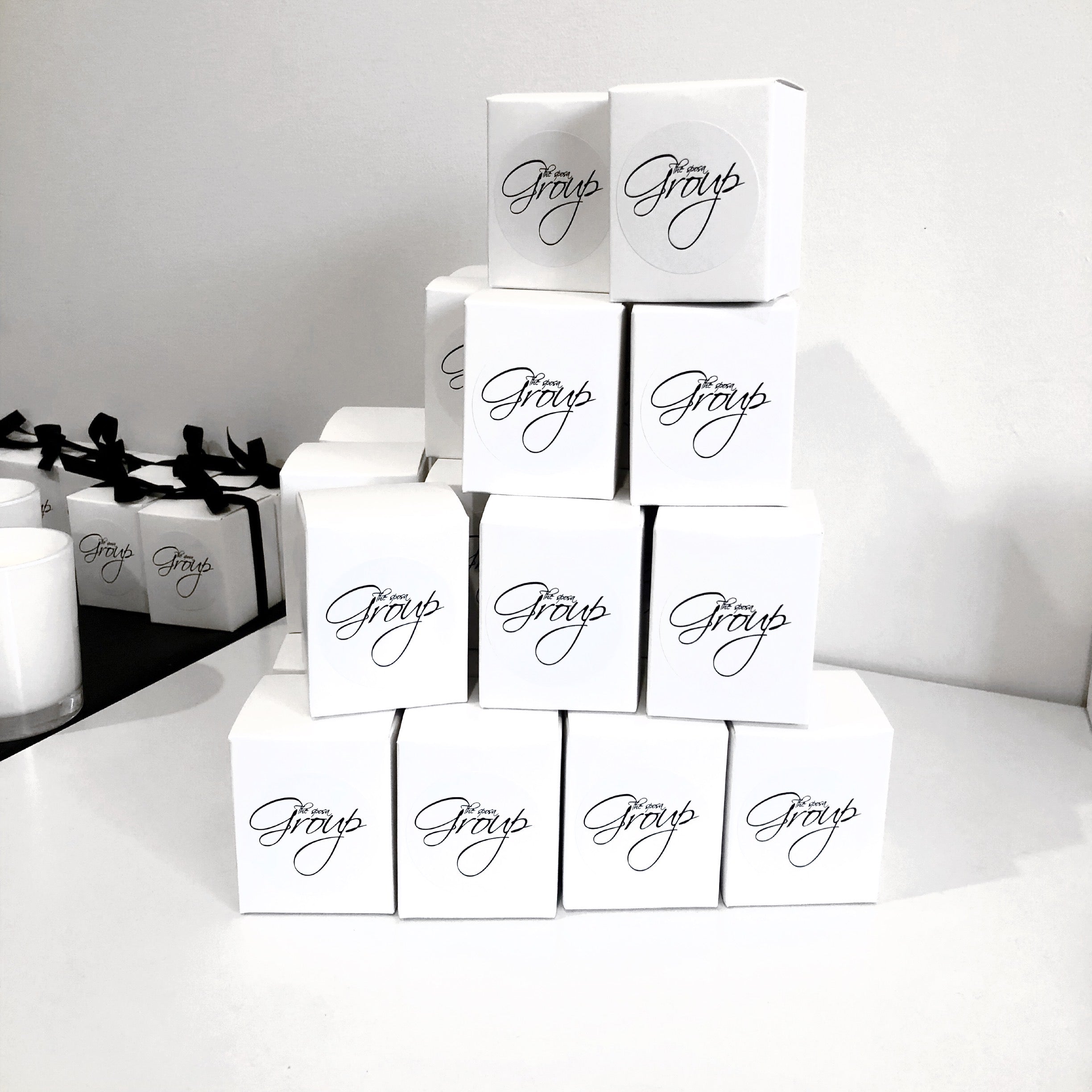 Elegant 60g custom branded candles for The Sposa Group arranged in a display stack. Minimal white packaging with script logo, ideal for bridal or client gifting.