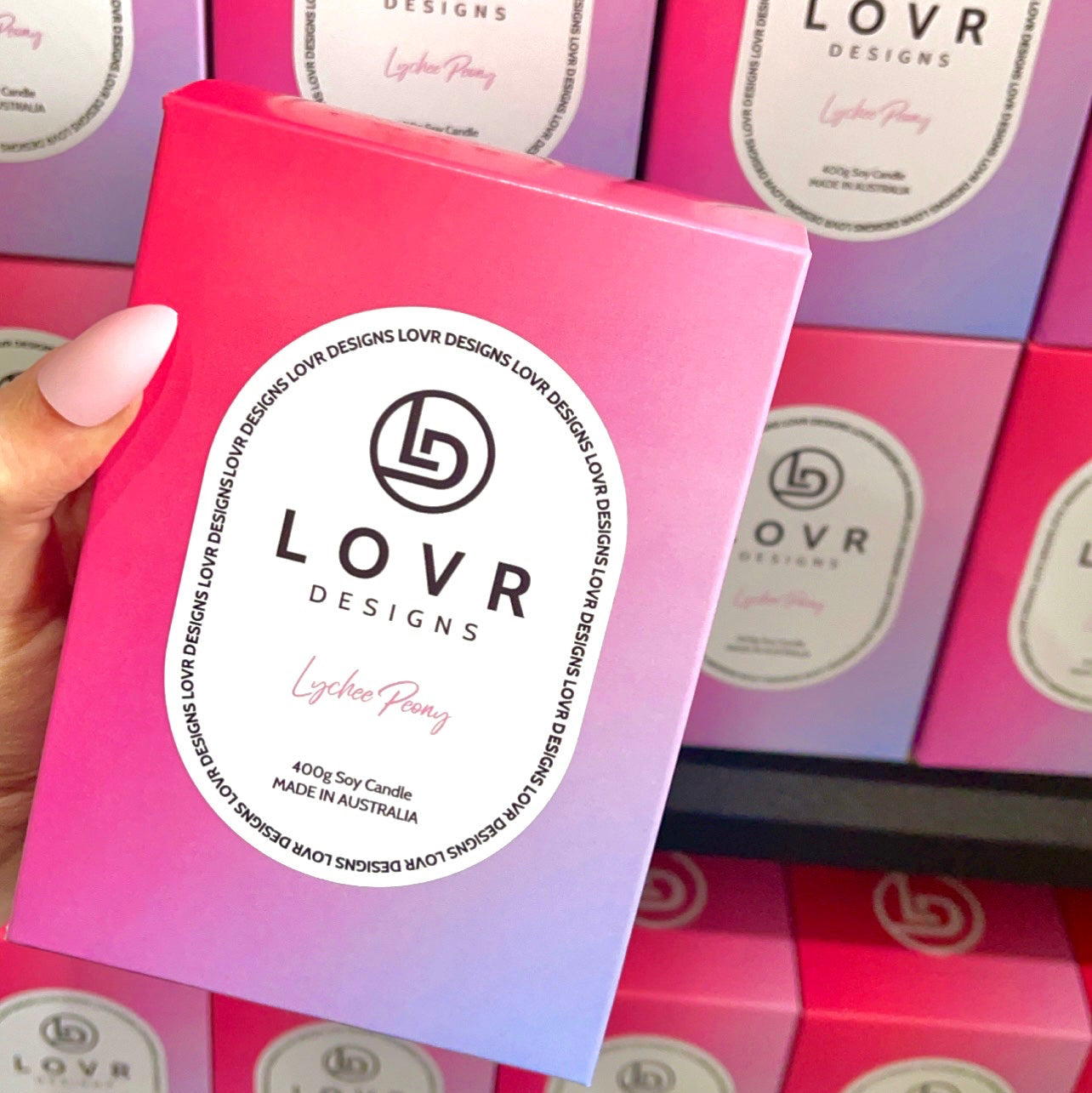 Close-up of Lychee Peony candle packaging with pink and purple ombre design, displayed on shelf at Lovr Designs.